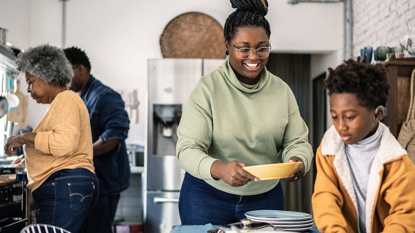 A family sets the table and preps a meal.